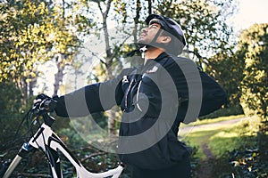 Forest, fitness and cyclist with back pain, bicycle and exercise adventure trail in nature. Cycling, woods and man with