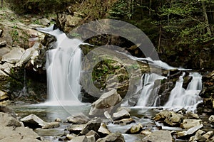 Forest flowing waterfall high up in the mountains of the Carpathians with noise flows down on a background of forest