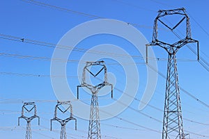 Forest of high voltage towers under blue sky