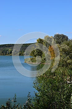 Forest lake in the autumn afternoon. Calm water with reflection of trees