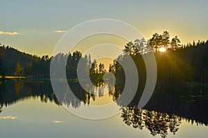 Forest lake in Sweden on a summer late afternoon, after sunset. Nydala lake in Umea under a blue-pink soothing sky.