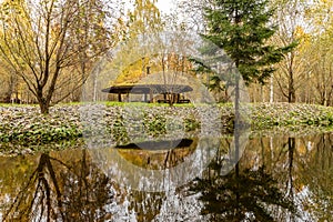 Forest lodge in backwoods, Wooden arbor, wild area in beautiful forest in Autumn, Specular reflection in water, Valday