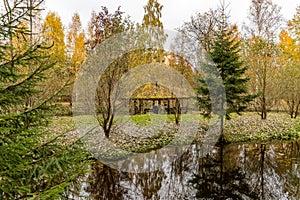 Forest lodge in backwoods, Wooden arbor, wild area in beautiful forest in Autumn, Specular reflection in water, Valday