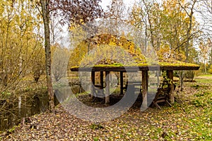 Forest lodge in backwoods, Wooden arbor, wild area in beautiful forest in Autumn, Specular reflection in water, Valday