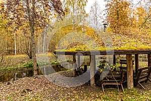 Forest lodge in backwoods, Wooden arbor, wild area in beautiful forest in Autumn, Specular reflection in water, Valday