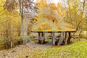 Forest lodge in backwoods, Wooden arbor, wild area in beautiful forest in Autumn, Specular reflection in water, Valday