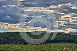 Forest and meadows in a cloudy day with sun beams