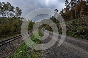 Forest path next to train tracks under storm clouds