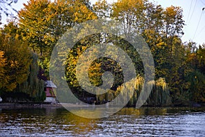 Forest reflected in the lake in autumn season. Beautiful landscape with colorful trees near the blue water