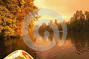 Forest reflection with boat on lake or river. Golden hour.