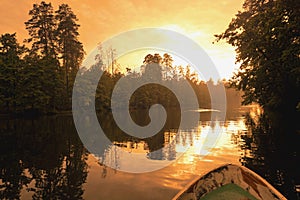 Forest reflection with boat on lake or river. Golden hour.