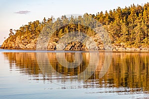 Forest and rocks reflecting in sea very early in the morning