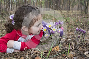 In the forest in the spring, a little girl lies on the ground an