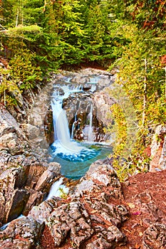 Forest surrounds peaceful blue waterfalls into rocky canyon