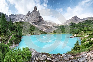 Forest and turquoise lake in the Dolomites apls, Italy.