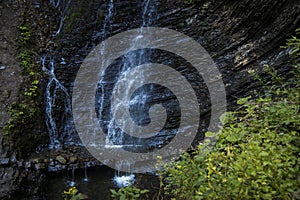 Forest waterfall water fuzzy motion rock cascade scenic view outdoor environment and green foliage foreground