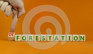 Forestation or deforestaion symbol. Ecologist turns wooden cubes and changes the word deforestation to forestation. Orange