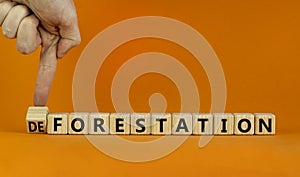 Forestation or deforestaion symbol. Ecologist turns wooden cubes and changes the word deforestation to forestation. Orange