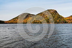 Forested mountain peaks in beautiful fall colors above a lake in Acadia National Park