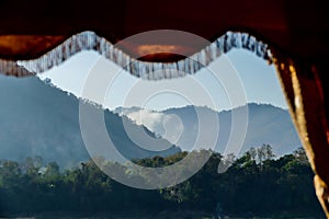 Forested mountain range seen through a curtain