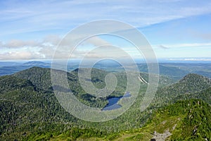 A forested valley with a beautiful blue lake in the middle, with the ocean in the background, on the west side of Graham island