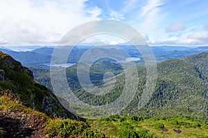 A forested valley with a beautiful blue lake in the middle, with the ocean in the background, on the west side of Graham island