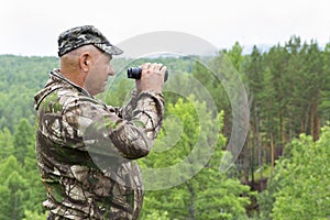 The forester looks through binoculars