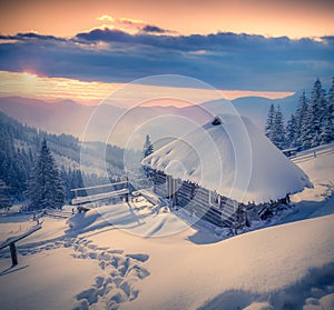 Forester's hut covered with snow in the mountains at sunrise.