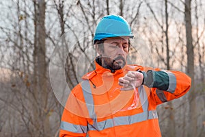 Forestry technician checking up on his smart watch