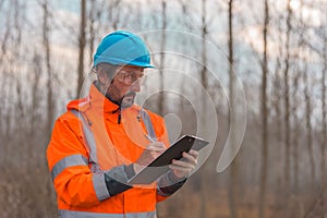 Forestry technician collecting data and writing at clipboard notepad