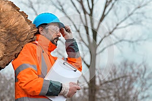 Forestry technician posing with clipboard notepad next to tree log