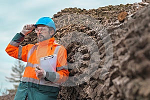 Forestry technician posing with clipboard notepad next to tree log