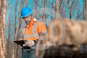 Forestry technician using digital tablet computer in forest