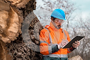 Forestry technician writing notes on clipboard notepad paper in forest