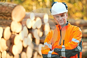 Forestry worker in protective workwear in front of wood lumber cut tree photo