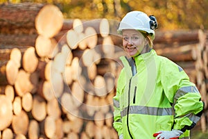 Forestry worker in protective workwear in front of wood lumber cut tree