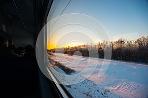 Forests and fields in the rays of dawn through the window of a speeding train