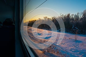 Forests and fields in the rays of dawn through the window of a speeding train