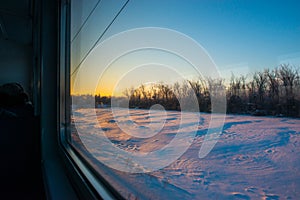 Forests and fields in the rays of dawn through the window of a speeding train