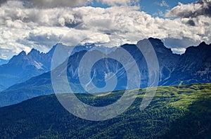 Forests, meadows and jagged peaks in blue mist Dolomites Italy