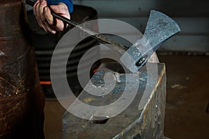 Creating iron tools in blacksmith`s on the old plank wood table