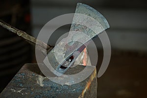 Creating iron tools in blacksmith`s on the old plank wood table