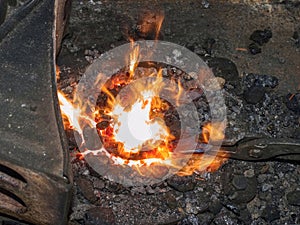 Forge with strong flames. Pliers hold horse shoe