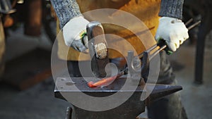 Forge workshop. Smithy manual production. Hands of smith with hammer hit on glowing hot metal, on the anvil, the forging