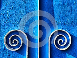 Forged metal detail on the blue gate. Decorative twisted iron element, hand-forged. Abstract background, texture, frame