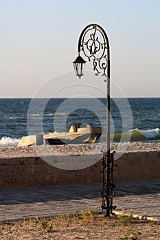 Forged park street lantern on the beach with a boats photo
