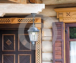 Forged plafond for lighting on the background of a wooden carved country house