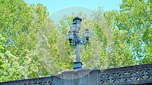 Forged street lamp standing on concrete bridge banisters