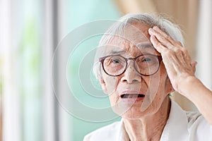 Forgetful asian senior woman with amnesia,brain disease,patient holding head with her hand,suffering from senile dementia,memory photo