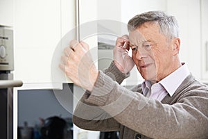 Forgetful Senior Man Looking In Cupboard